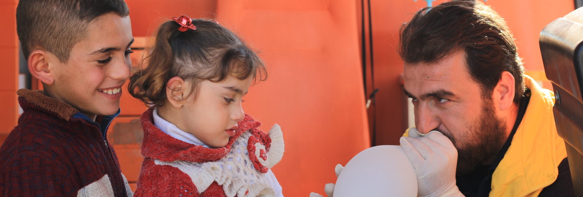 A man inflating a balloon for refugee children